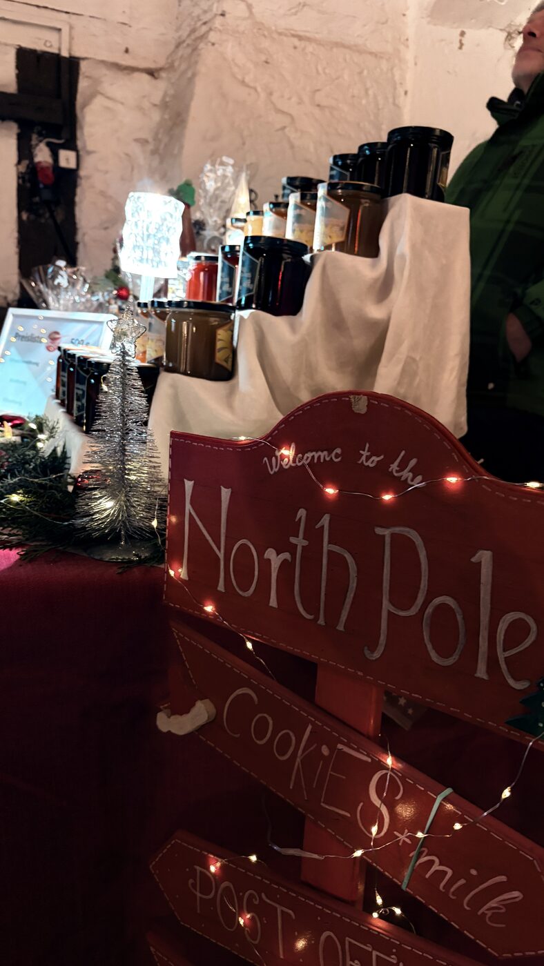 Weihnachtlicher Stand mit North-Pole-Schild und Lichterketten