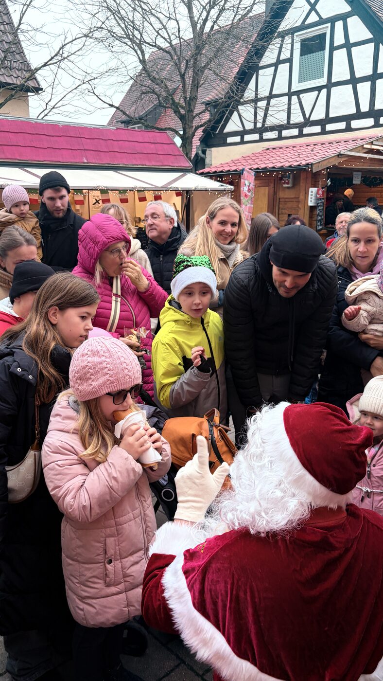 Der Nikolaus verteilt Geschenke an Kinder auf dem Weihnachtsmarkt